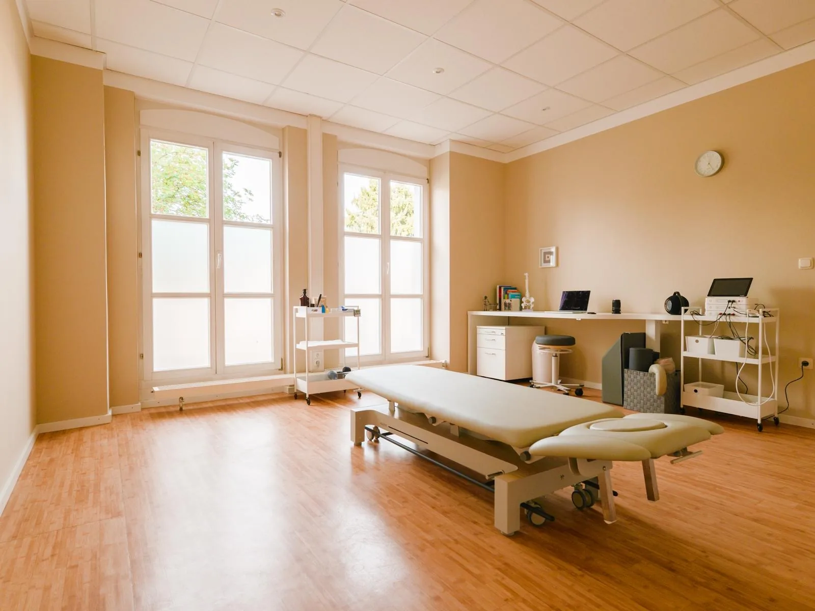 Behandlungsraum der Physiotherapie Wick in Eggenfelden — Behandlungsliege vor hohen Fenstern mit Tageslicht