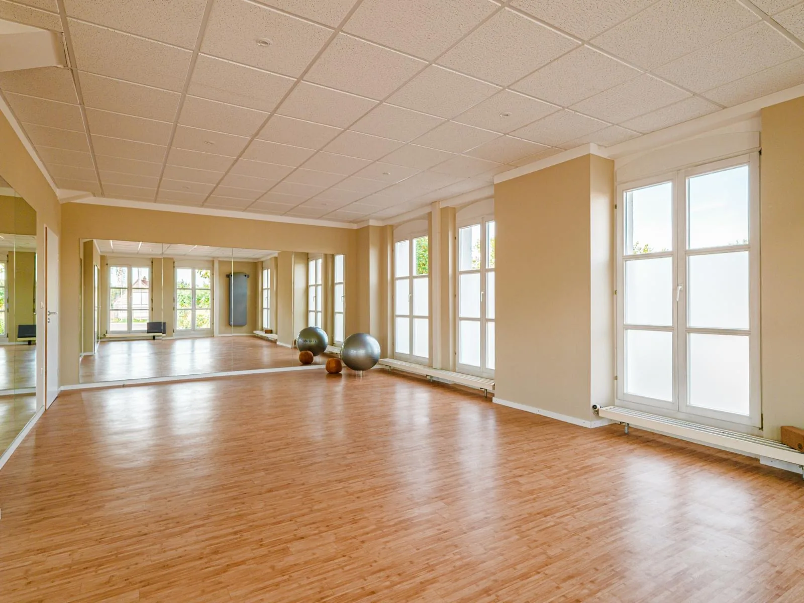 Kurs- und Trainingsraum der Physiotherapie Wick mit Spiegelwand und Fensterfront